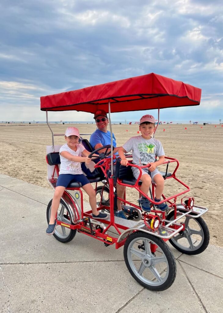 family riding in a quad bike along the beach boardwalk