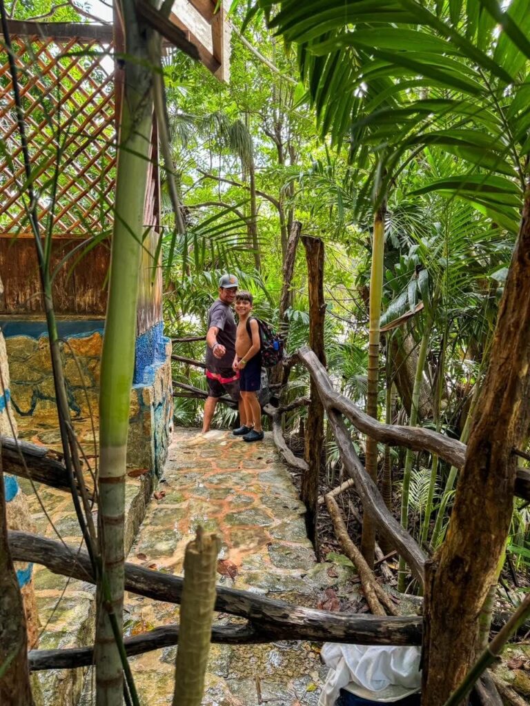 Boy and his father standing on a path in the jungle near the open air showers at Cenote Azul