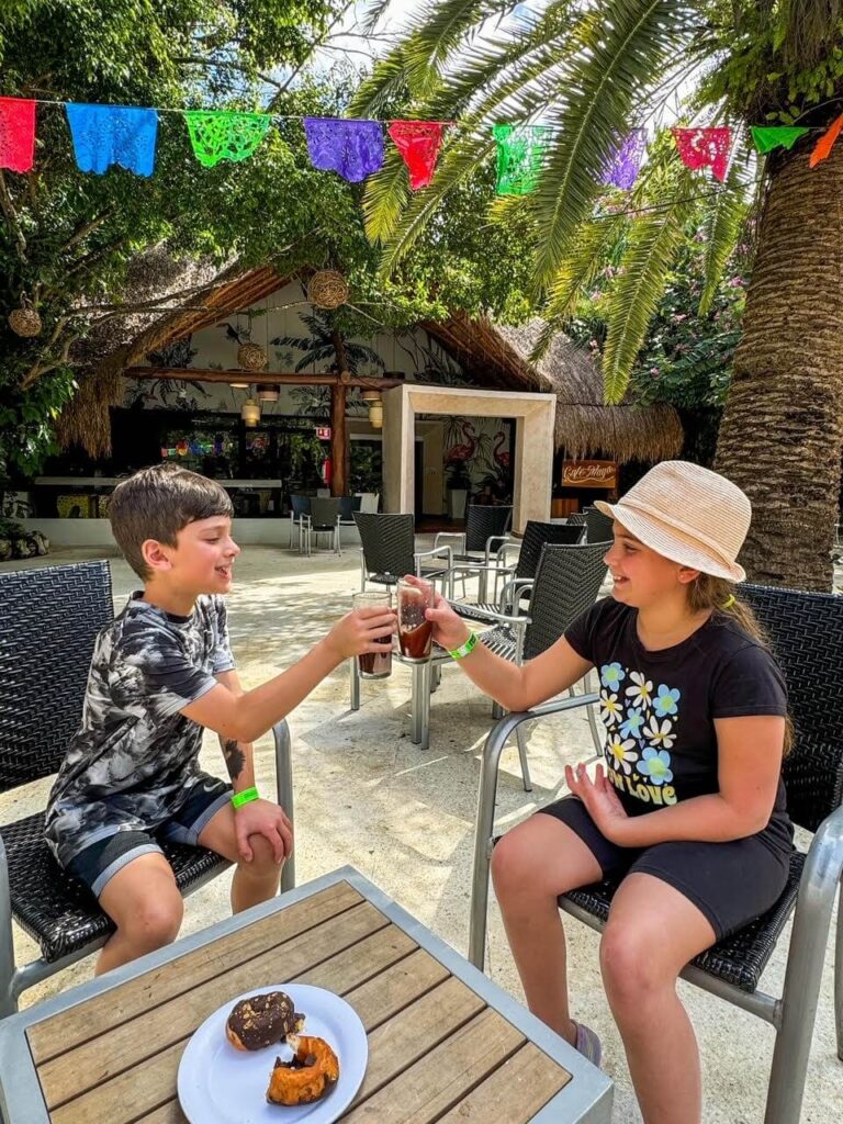 boy and girl each holding a glass with chocolate smoothie and saying "cheers" while clinking their glasses. 