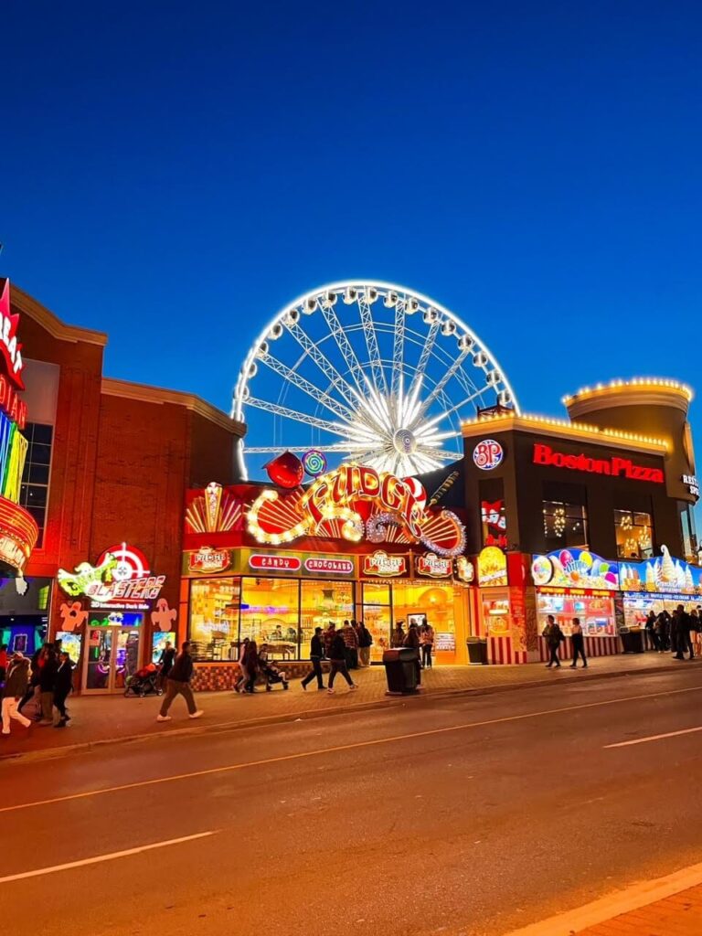 Clifton Hill Niagara Falls lit up at night. Boston Pizza, Fudge Store and the Skywheel all in the photo.