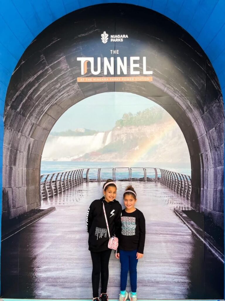 2 girls posing in a picture at Table Rock. The picture is of the entrance to the tunnel at Niagara Parks Power Station.