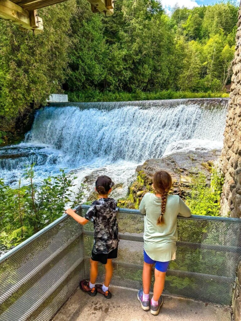 2 kids standing in front of belfountain waterfall