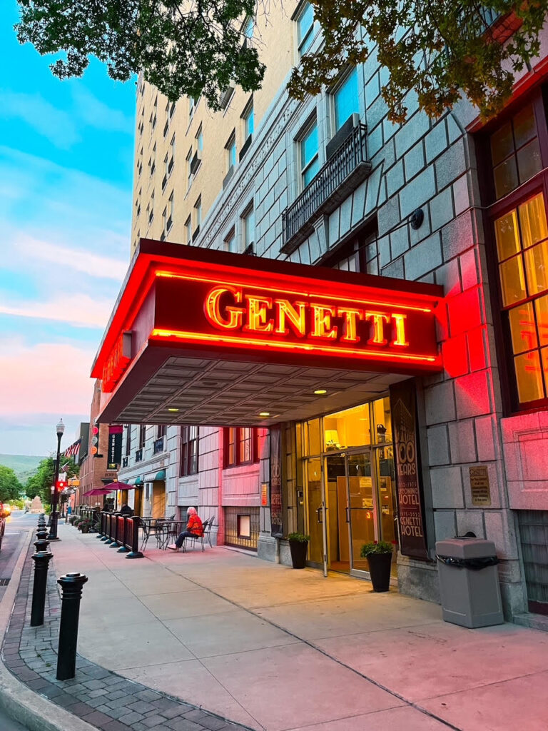 A picture taken from outside of the Genetti Hotel, a bright neon sign. 