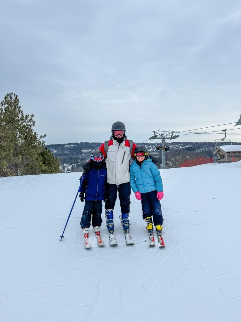 dad and 2 kids at the top of the mountain getting ready to ski at Horseshoe Valley Resort