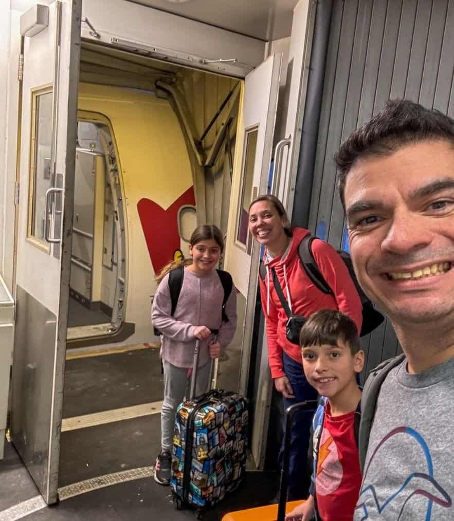 Family of 4 boarding a plane with carry on suitcases