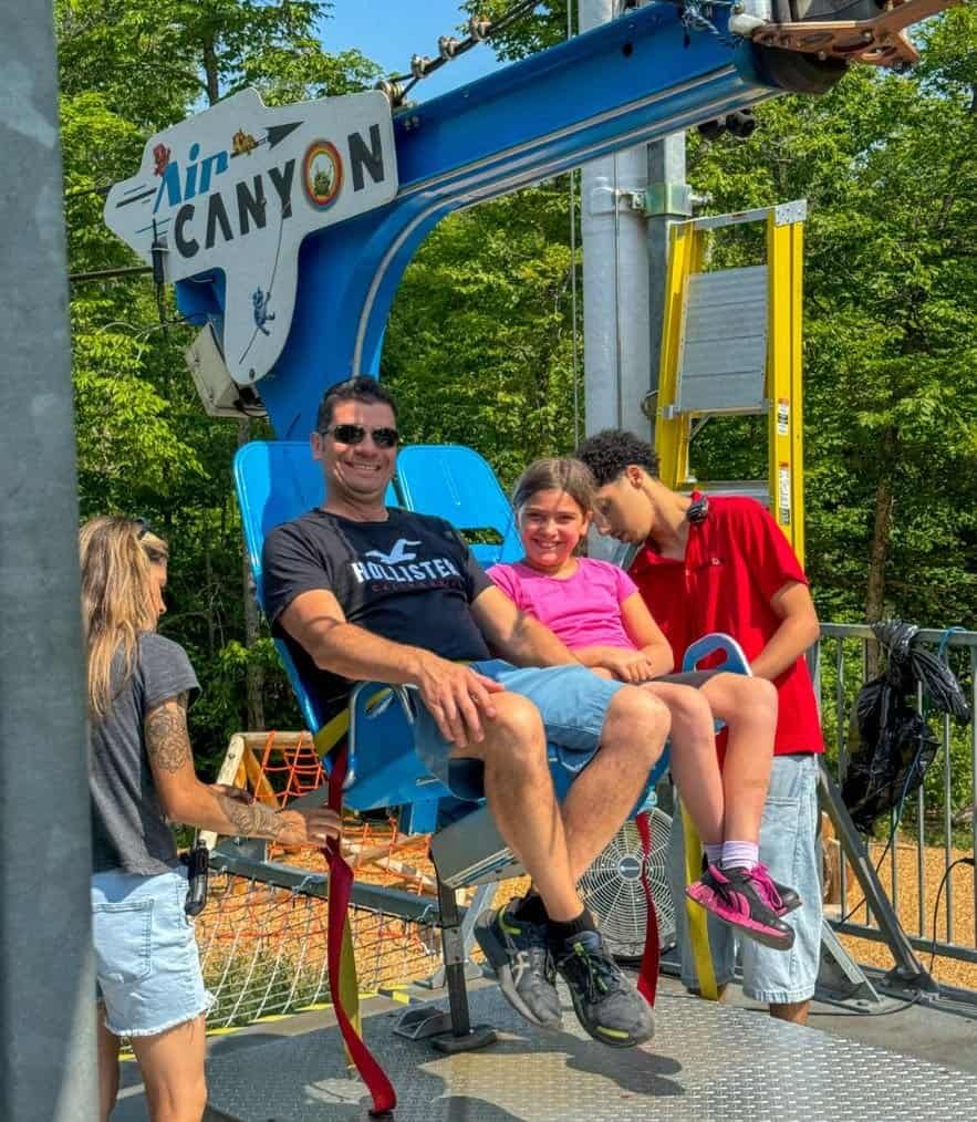 dad and daughter getting buckled up into a swing over St. Anne Canyon