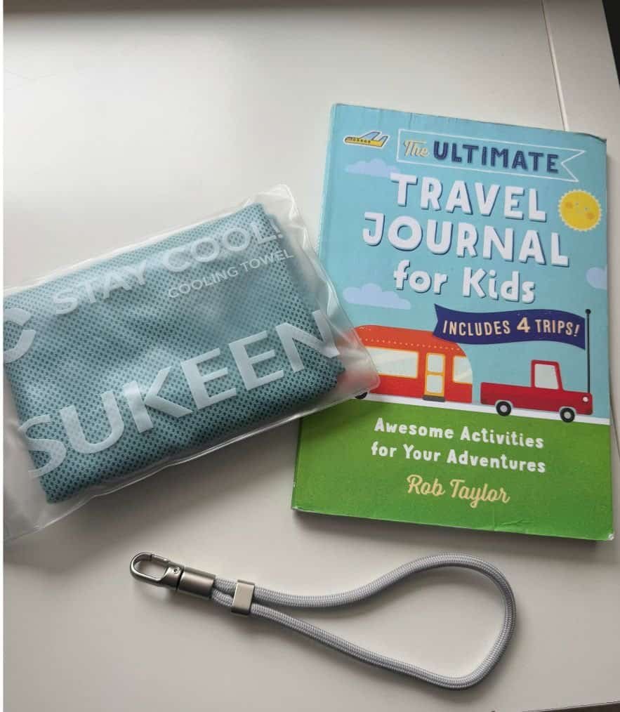 a few packing items like cooling towel, kids travel journal and a phone wrist strap