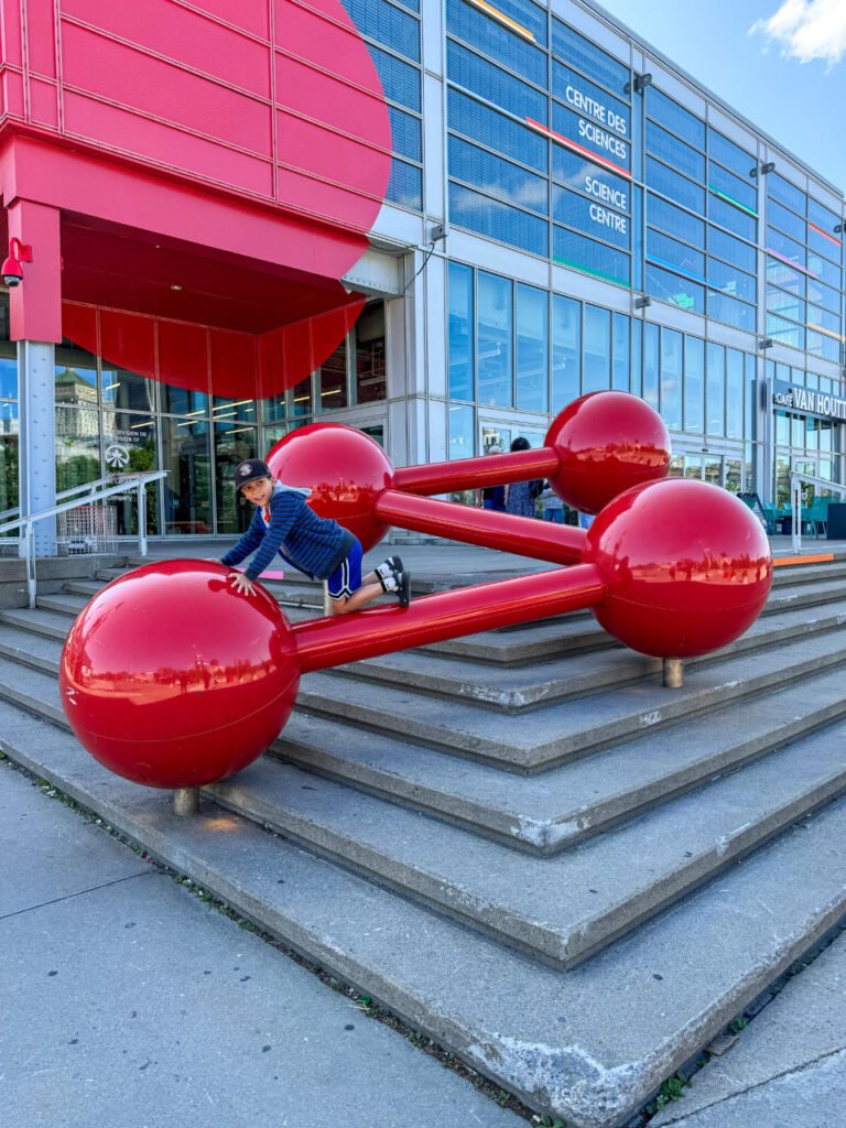 A boy climbing on red structures outside the science centre in the Old Port Montreal