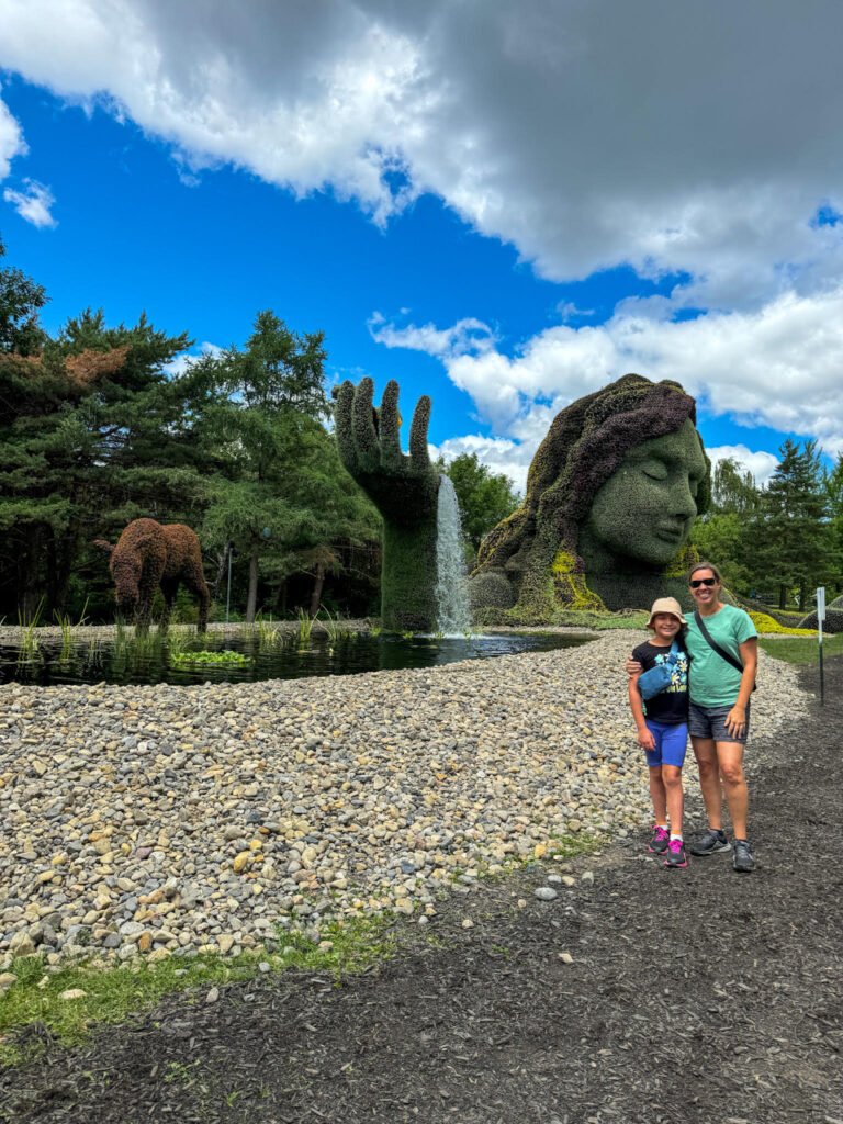 Mom and daughter posing in Parc Jean-Drapeau with the beautiful sculptures that look like a woman with her hand holding a waterfall.