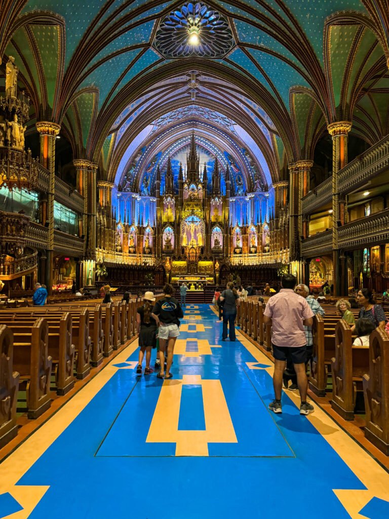 Inside Notre Dame Basilica, bright blue and yellow floors and looking up to the back of the church at the organ. Also showing the detailed blue roof. 