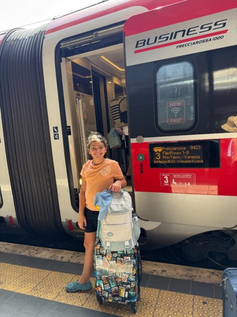 girl standing beside italy train door that reads business class